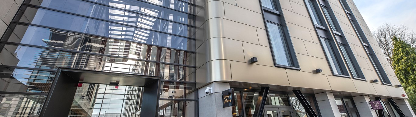 Outside front view of hotel exterior. Modern look gold and black building with multiple glass window panels