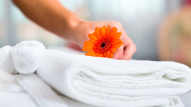 Close up view of a orange flower above of a folded white towel.