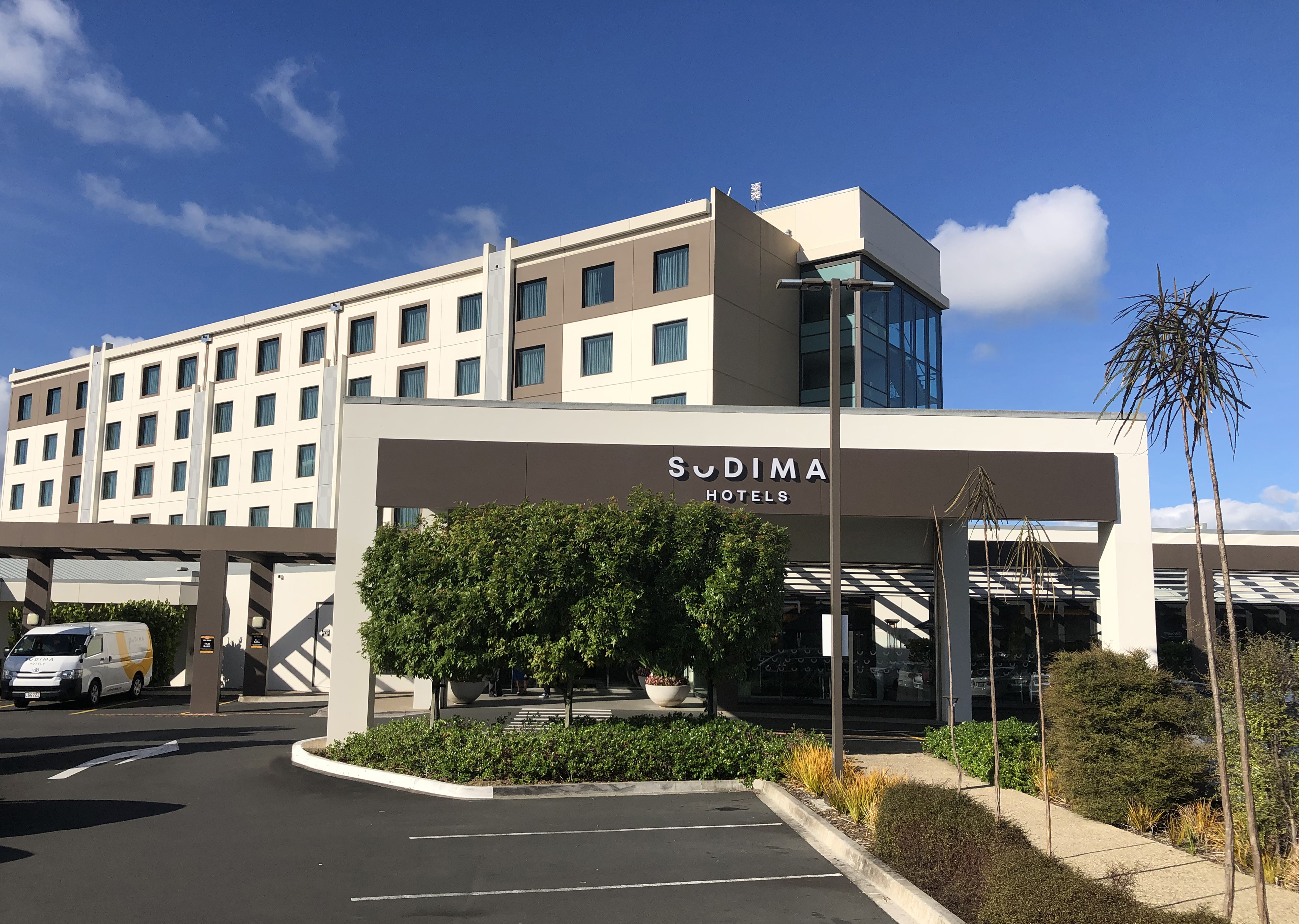 Outside front view of hotel exterior. Cream and brown building with carpark out front.