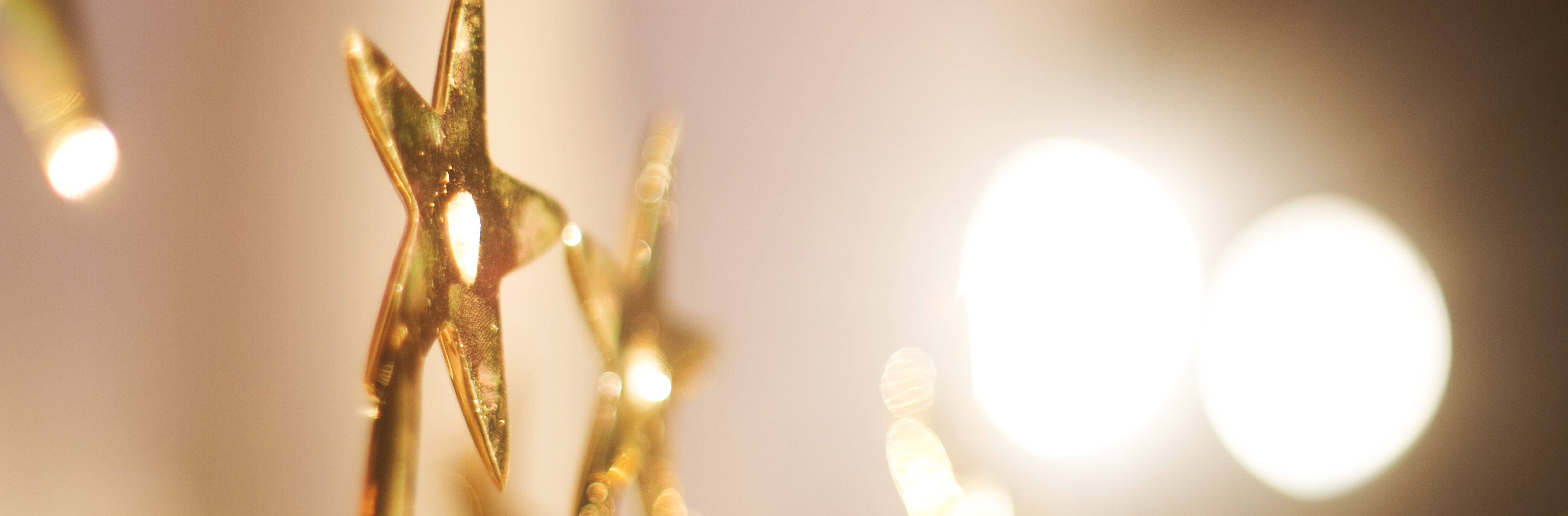 Close up side view of a gold metal star illuminated by bright lights.