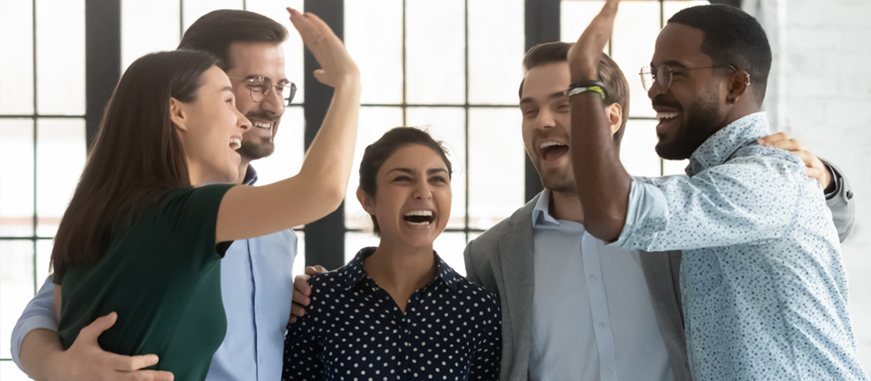 Front view of a group of people celebrating together while doing high-fives and laughing with each other.